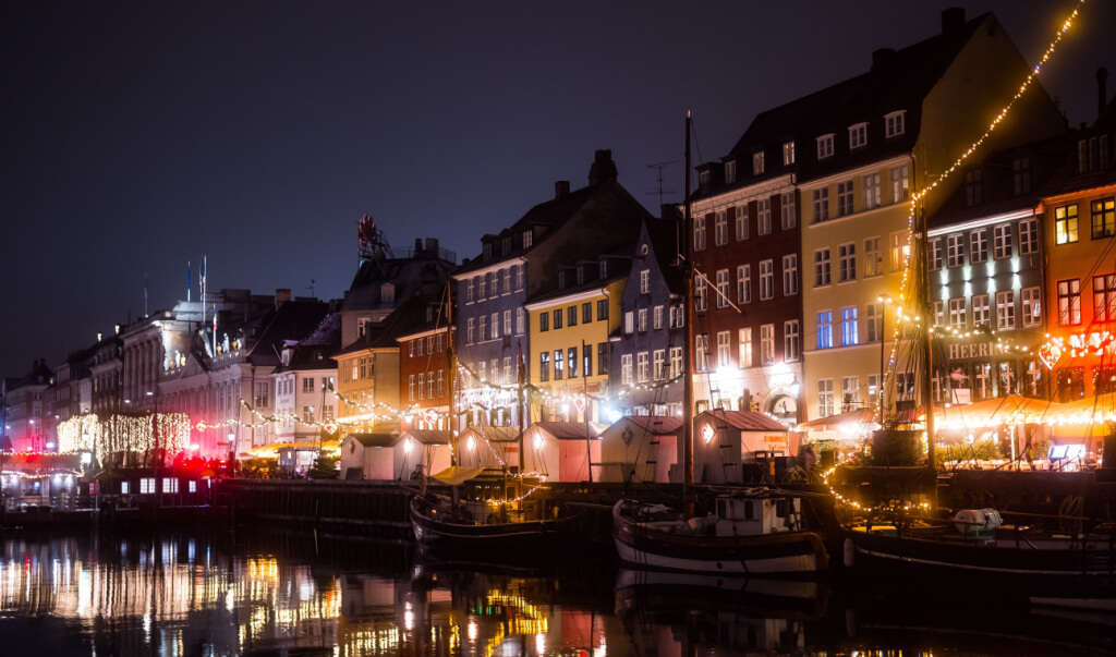 Copenhagen, Denmark. Nyhavn canal at night showing the beautiful street and historic boat decorated with christmas lights during the winter season.