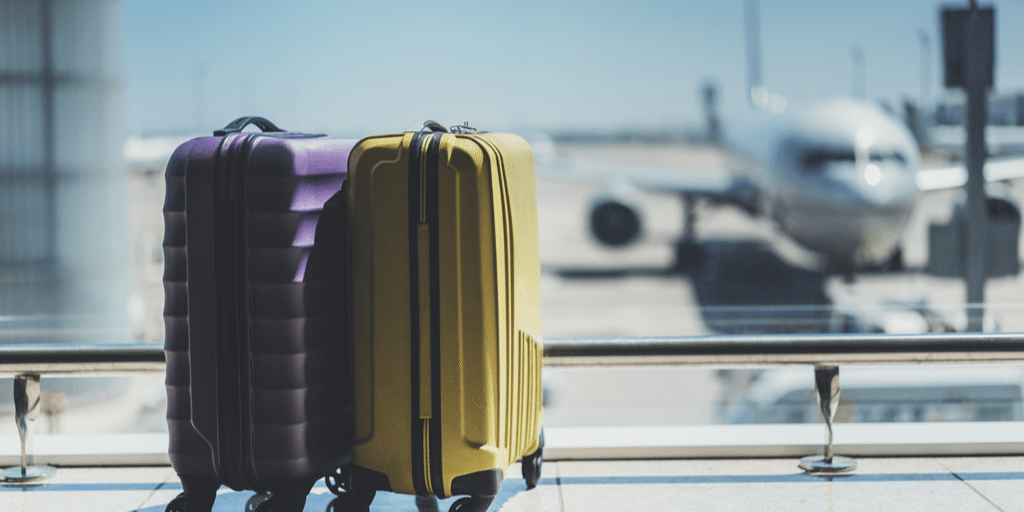 two carry-on bags at airport with airplane in window